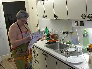 Hot granny Gerlinde washes the dishes naked, wearing only a kitchen gown. She becomes turned on because she has not played for a while now. The old slut starts squeezing her saggy boobs and takes off her white panties so that she could reach more easily her moist cunt. What`s she doing laying naked on the floor?