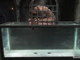 Scarlet though things are rough for her when she was hanging tied up and the executor was drilling her cunt with a dildo. Little did she know that he had something a lot more interesting for her moist sexy body. She discovered out when he putted her in that cage and started to submerse her in the water tank